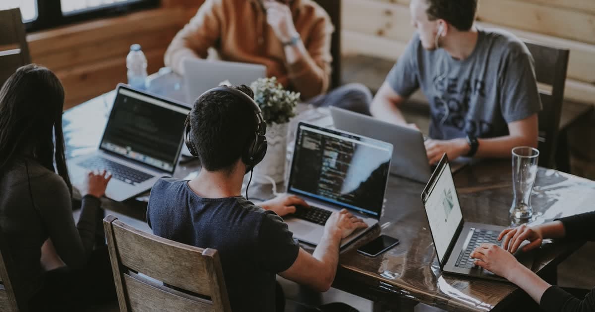Team collaborating around a shared workspace, representing multiplayer AI agent work
