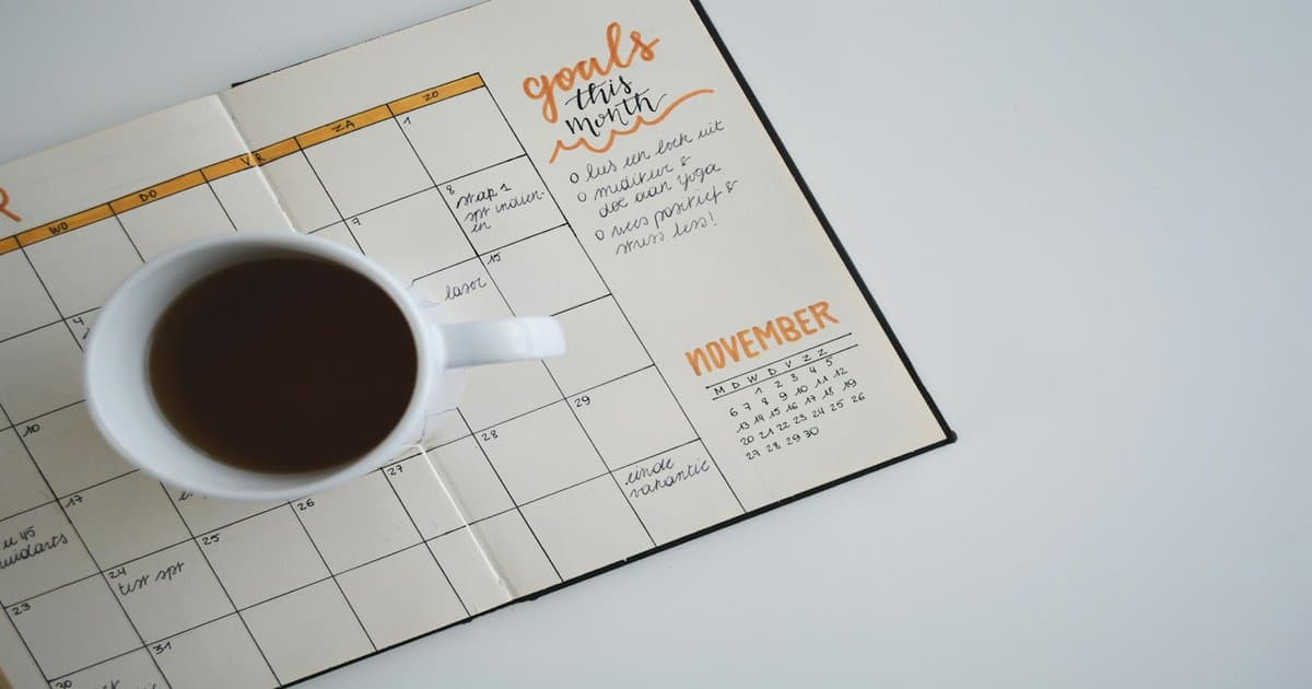 Desk calendar and laptop on a workspace, representing AI agents that run on schedules and act without waiting for a prompt