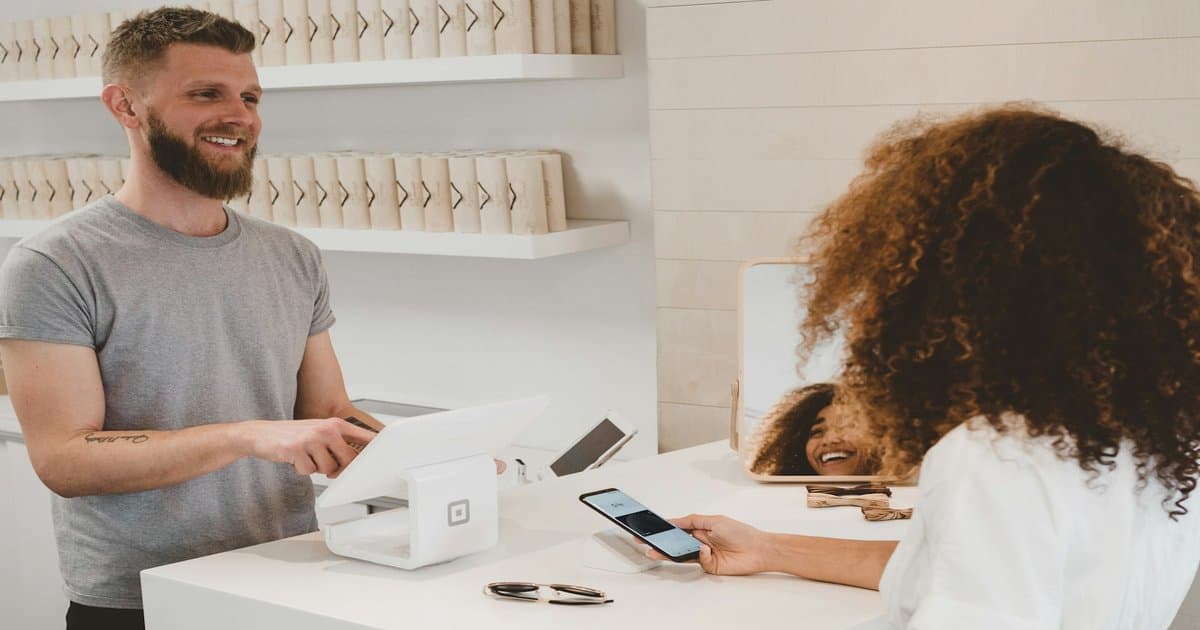 Customer holding a credit card next to a laptop showing an online store, representing AI agents that shop and pay on behalf of people